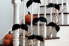 branches with black bats attached to the railing and pumpkins on the steps for Halloween decor