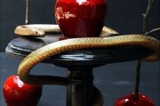 candied apples served on a stand and accented with a gold snake for Halloween
