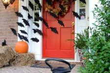 hay, pumpkins, black bats and a dried bloom wreath on the door make the front porch Halloween-like