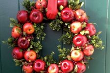 a fall wreath of boxwood, red apples, berries and a red ribbon is bright, fun and a bold option
