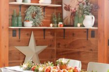 farmhouse fall decor with greenery, apples, a wooden tray with apples and a planter with a candle