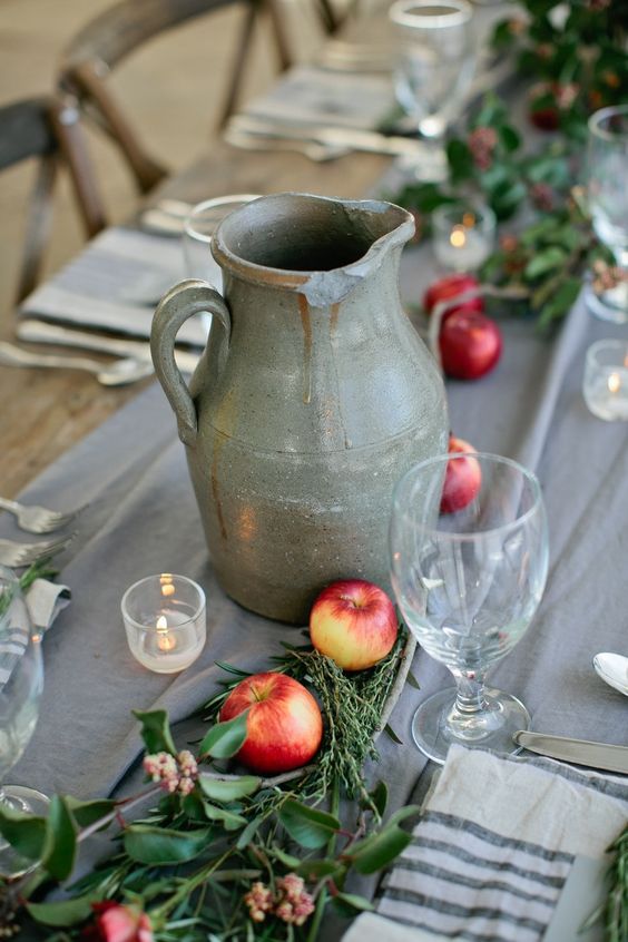 rustic table decor with a grey table runner, a vintage jug, apples and greenery right on the table