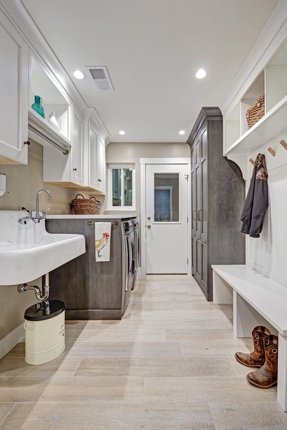 a neutral farmhouse mudroom and laundry with white shaker cabinets, a wall-mounted sink, wardrobes and a bench is cozy and cute