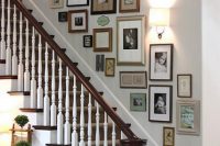 an eclectic stairway gallery wall with mismatching frames and artwork, photos and monograms and a sconce to accent them