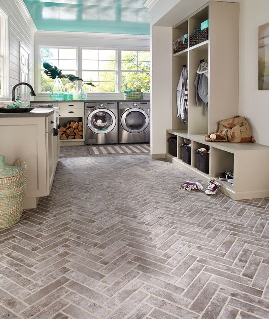 an L-shaped mudroom laundry with a tile floor, neutral furniture, built-in appliances, some open racks and a basket