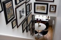 a bold gallery wall with photos and art, in mismatching black and just dark-stained frames taking two walls