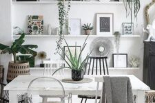 a boho Scandinavian living room with ledges with artwork, potted plants and mirrors, a white table and mismatching chairs