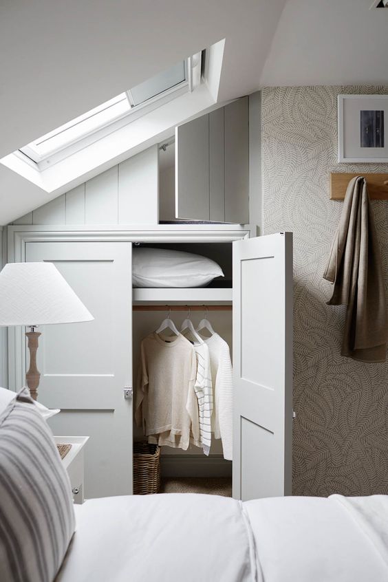 a cabinet built in under the attic ceiling is a cool and sleek idea for a small bedroom, it won't take much space