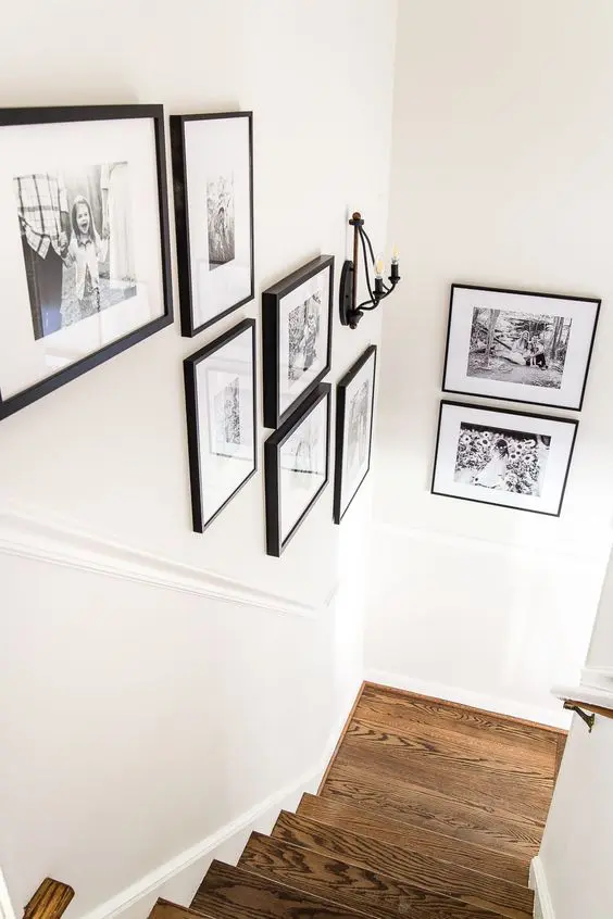 a catchy black and white gallery wall of family photos in black frames is a lovely idea for a modern rustic space