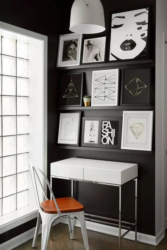 a catchy mini home office with black ledges on a black wall and bold graphic artwork, a small desk and a chair