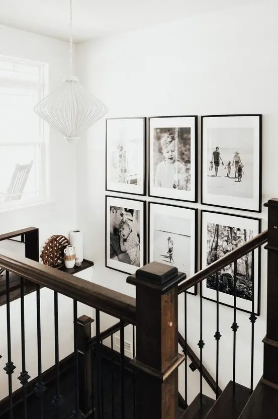 a chic black and white grid gallery wall with matching black frames and white matting adds style and a modern fele to the space