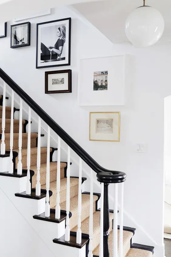 a chic gallery wall with black and white photos and frames and a small artwork in a gold frame is wow