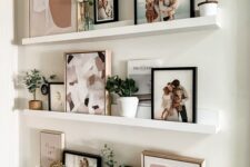 a cool ledge gallery wall with art, small plants in pots and family pics is a cool idea for a modern home