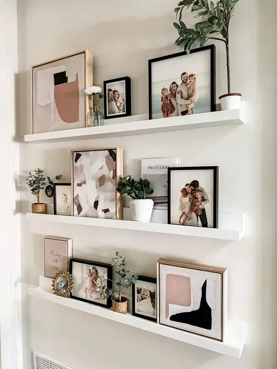 a cool ledge gallery wall with art, small plants in pots and family pics is a cool idea for a modern home