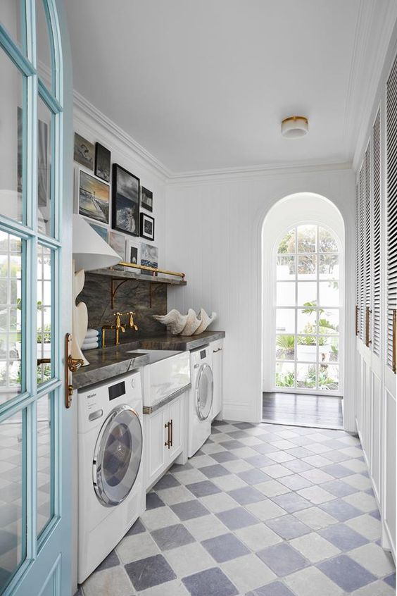 a cool mudroom laundry with white cabinets, a sink and appliances and wardrobes with shutter doors that hide the mudroom part