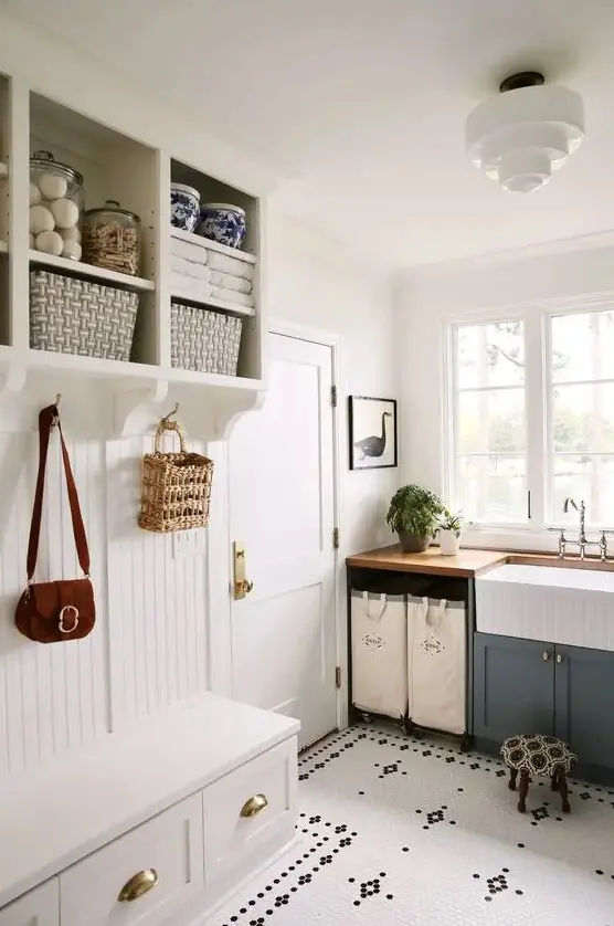 a cozy laundry mudroom with a beadboard rack with drawers and open storage, a grey cabinet and a sink plus a penny tile floor