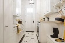a creamy laundry mudroom with shaker cabinets, a hex tile floor, a bench with storage, a washing machine and a dryer and pendant lamps