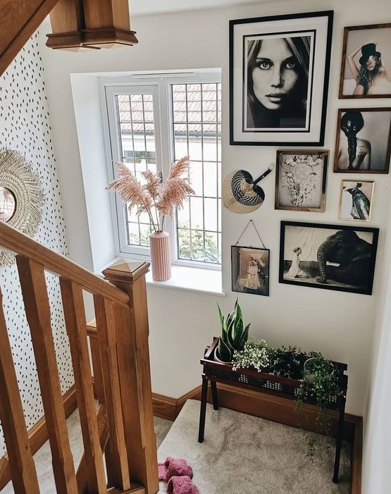 a creative free form gallery wall with mismatching frames, black and white artworks and a fan to style this space