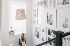 a free form gallery wall with black and white family pics and white frames si a very chic and stylish idea for any space