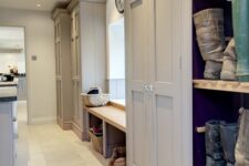 a grey farmhouse laundry mudroom with storage wardrobes, a bench with storage and a kitchen island with appliances