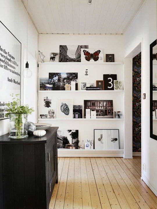 a large ledge gallery wall from floor to ceiling, with black and white and colored artwork and photos is a cool idea