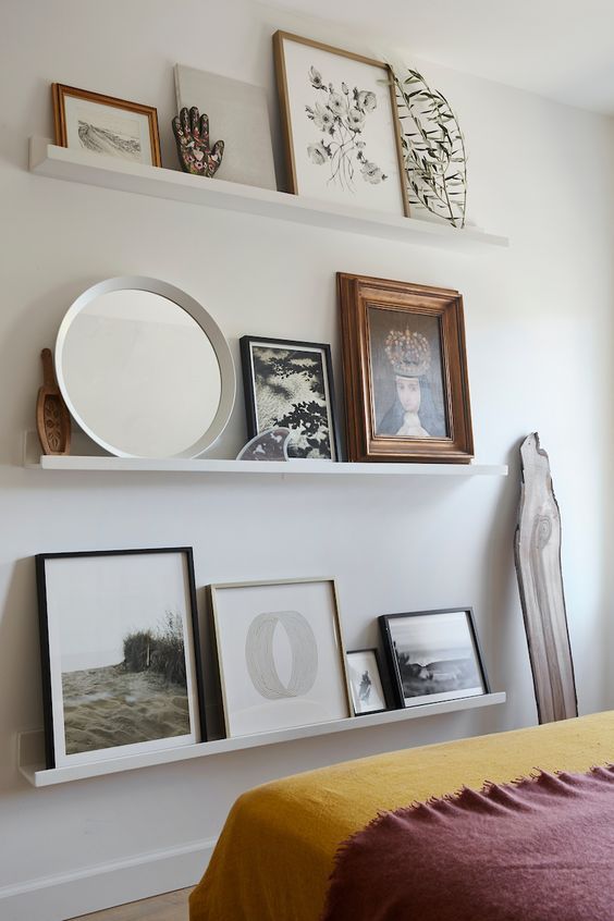 a ledge bedroom gallery wall with a mirror, some art and photos and some addition decor is a cool solution