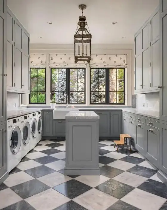 a light grey farmhouse mudroom laundry with shaker cabinets, a checked floor, printed curtains and a pendant lamp