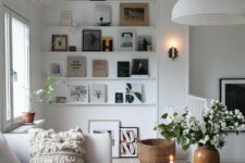 a lovely Scandinavian living room in neutrals with ledges that display art and books, a neutral sofa with a blanket and pillows, some decor