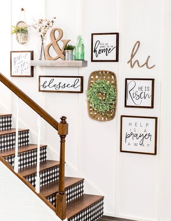 a lovely rustic gallery wall with signs in stained frames, a greenery wreath, a shelf with potted grass and an ampersand and a green bottle