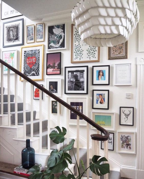 a maximalist gallery wall with super bright artwork and posters in black and white frames looks very statement-like