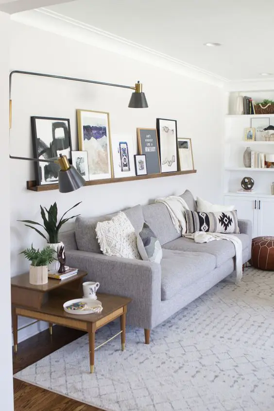 a mid-century modern living room with built-in shelves, a stained ledge with art, a grey sofa, a printed rug and a leveled coffee table