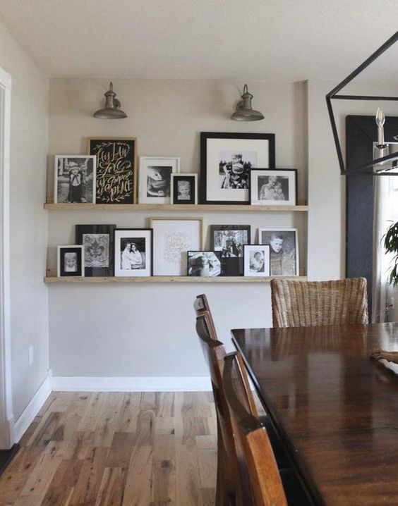 a modern farmhouse space with a stained table and woven chairs, ledges and black and white artwork