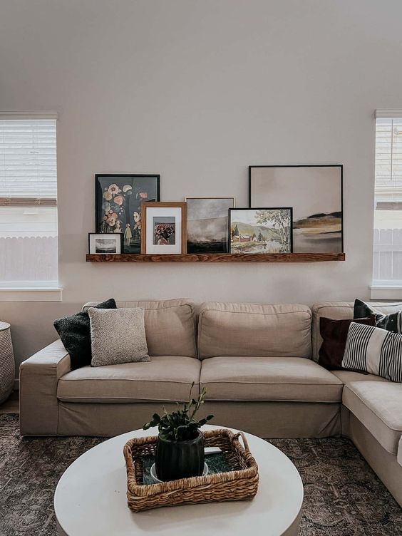 a modern living room with a tan sectional, a coffee table, a printed rug and a stained ledge with art