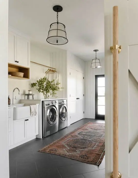 a neutral farmhouse mudroom laundry with built-in cabinets, appliances, a sink, a rug and pendant lamps