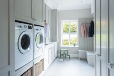 a neutral laundry and mudroom with shaker cabinets, a storage bench, baskets and a washing machine and a dryer