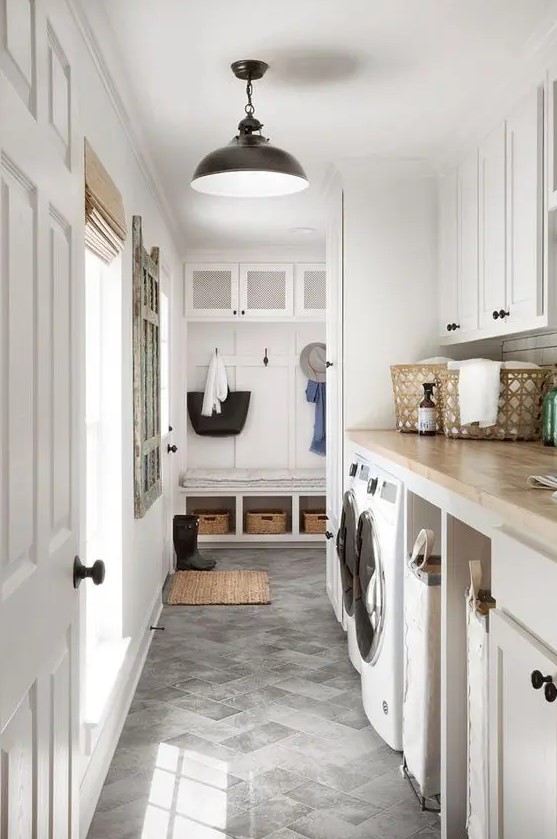 a neutral mudroom laundry with shaker cabinets, butcherblock countertops, a washing machine and a dryer plus black fixtures