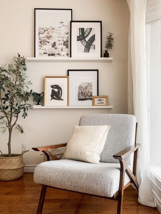 a neutral nook with a grey chair, a small ledge gallery wall with art, a potted tree and some baskets is a cool space