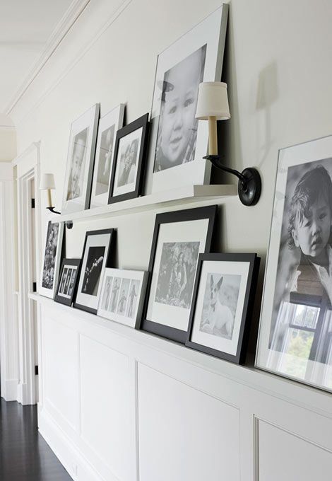 a neutral wall with paneling, ledges and black and white artwork plus sconces is a cool and cozy idea