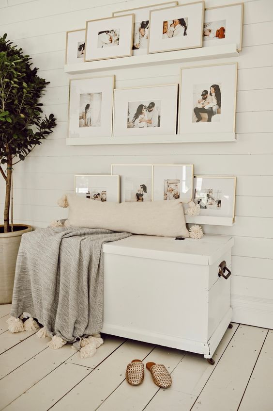 a paceful nook with neutral ledges and family photos, a white chest that doubles as a bench, a pillow and a blanket