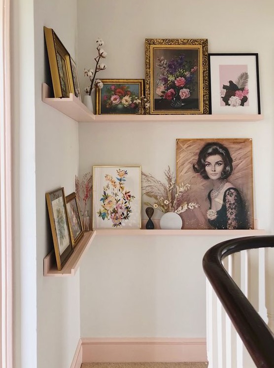 a refined gallery wall done with blush corner ledges, vintage artworks in gold and black frames, dried leaves and blooms in vases