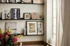 a refined gallery wall with black ledges and chic colored and black and white artworks, vases and photos is very cool and bold