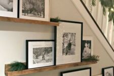 a rustic gallery wall with stained wooden ledges attached to the staircase, black and white artworks and greenery is cool