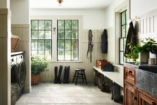 a rustic mudroom laundry with a stone floor, appliances, a bench, a stained storage piece and potted plannts