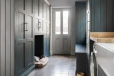 a slate grey mudroom laundry with shaker cabinets, a storage bench, a pet bed and a washing machine and a dryer