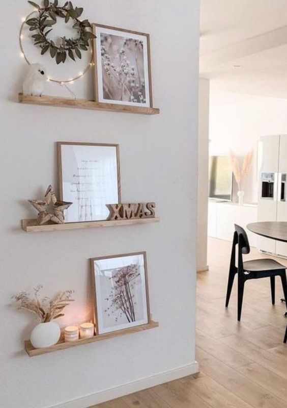 a small and lovely gallery wall with stained ledges, some art, wooden decor and candles is a cool idea