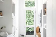 a small and narrow laundry mudroom with open shelves, built-in appliances and a glazed door plus a black pendant lamp