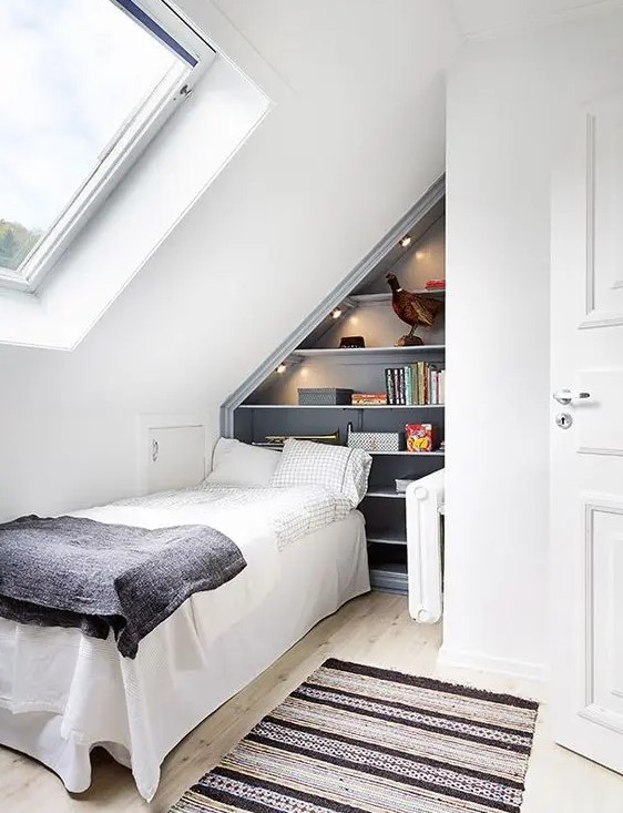 a small attic guest bedroom with a grey attic shelving unit built in, a bed and some lights is a very cozy space to stay in