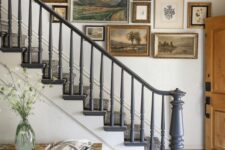 a sophisticated gallery wall with vintage artwork and mismatching frames for a vintage farmhouse entryway