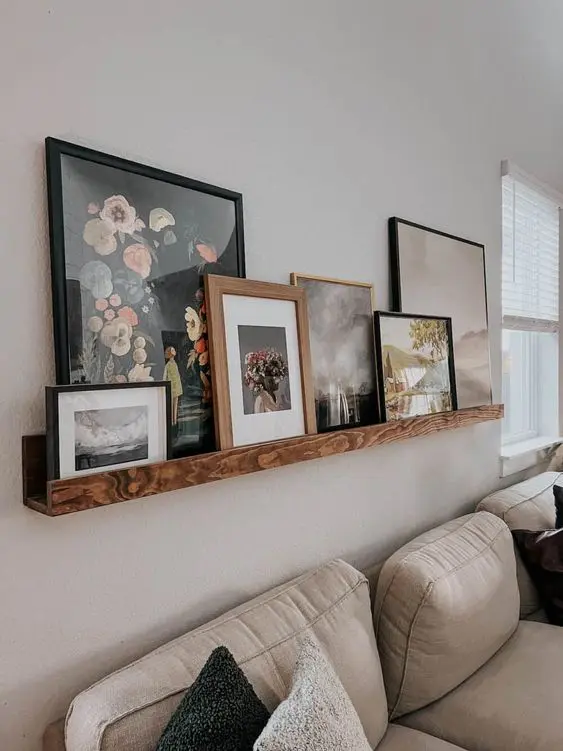 a stained ledge featuring bold and catchy artwork in mismatching frames is a cool decor idea for the space