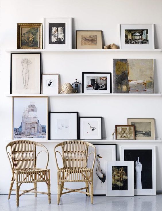 a stylish modern nook with thin ledges and various kinds of artwork, rattan chairs and some more art on the wall